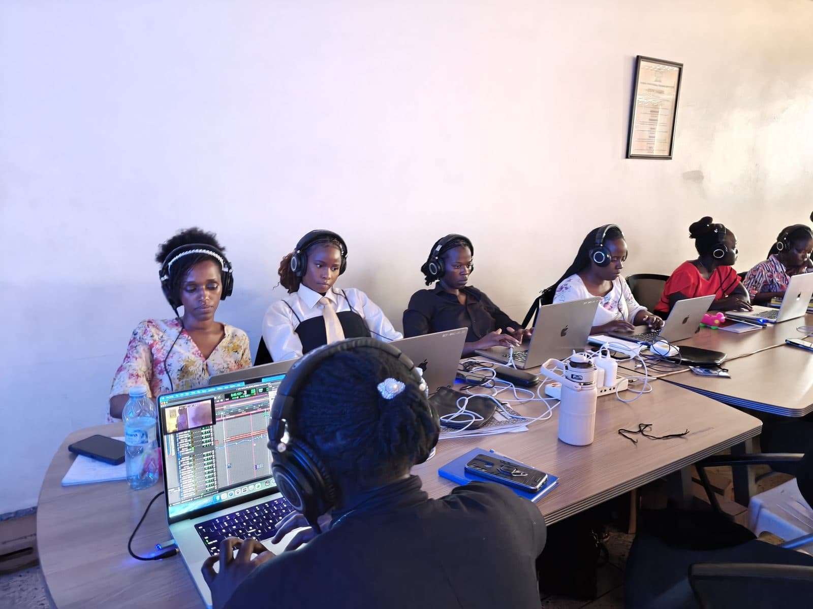 Mulika Sound School students in headphones working in a DAW on laptops around a table